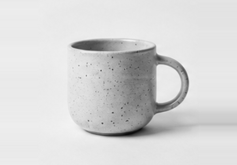 A speckled, hand-thrown stoneware mug, photographed in black and white.